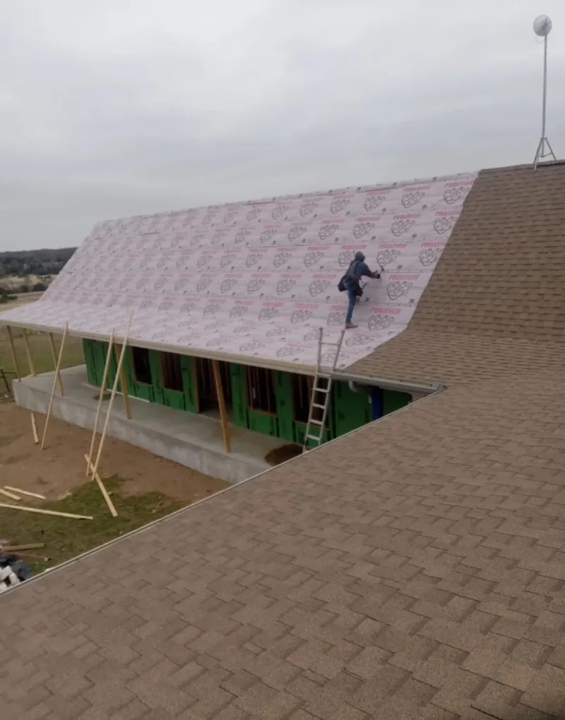 Worker preparing underlayment for a metal roof installation in Oakville